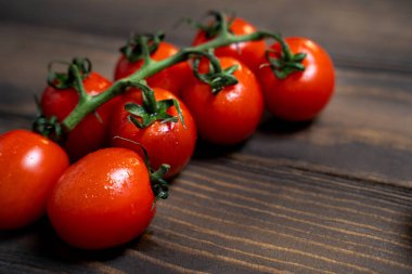 Fresh cherry tomatoes on a dark wood background.