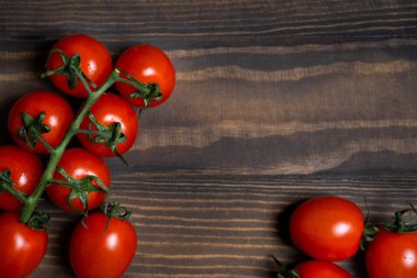 Fresh cherry tomatoes on a dark wood background.