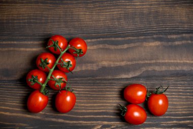 Fresh cherry tomatoes on a dark wood background.