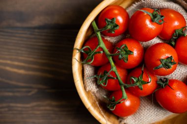 Koyu ahşap arka plan üzerinde bir tabakta taze kiraz domates.