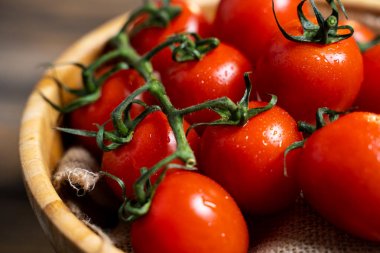 Koyu ahşap arka plan üzerinde bir tabakta taze kiraz domates.