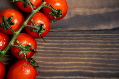 Fresh cherry tomatoes on a dark wood background.