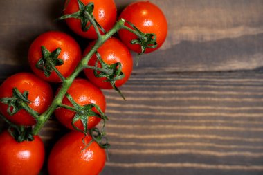 Fresh cherry tomatoes on a dark wood background.