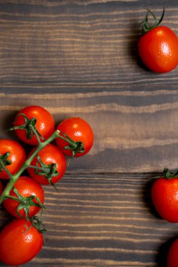 Fresh cherry tomatoes on a dark wood background.