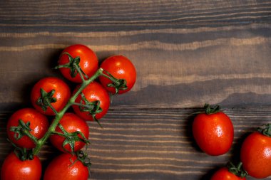 Fresh cherry tomatoes on a dark wood background.