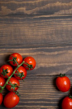 Fresh cherry tomatoes on a dark wood background.