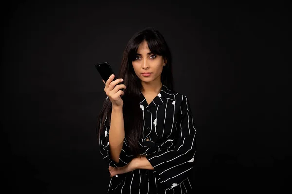 Joven chica de negocios en un traje negro posando para una foto sobre un fondo negro . — Foto de Stock