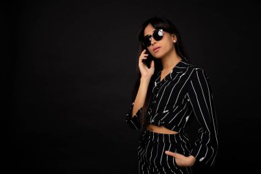 Siyah bir elbise bir siyah arka planda bir fotoğraf için poz genç iş kızı.