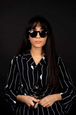 Siyah bir elbise bir siyah arka planda bir fotoğraf için poz genç iş kızı.