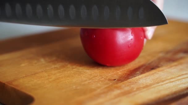 Manos masculinas cortan tomates jugosos frescos en una tabla de madera con un cuchillo afilado — Vídeos de Stock