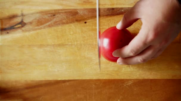 Manos masculinas cortan tomates jugosos frescos en una tabla de madera con un cuchillo afilado — Vídeos de Stock