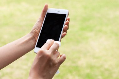 Taylandlı kadın ellerini alkol havlusuyla sildi ve akıllı telefonları yıkadı. El hijyen Corona virüsü koruması için Coronavirus önleme. COVID-19 önleme içeride dezenfekte ediliyor.