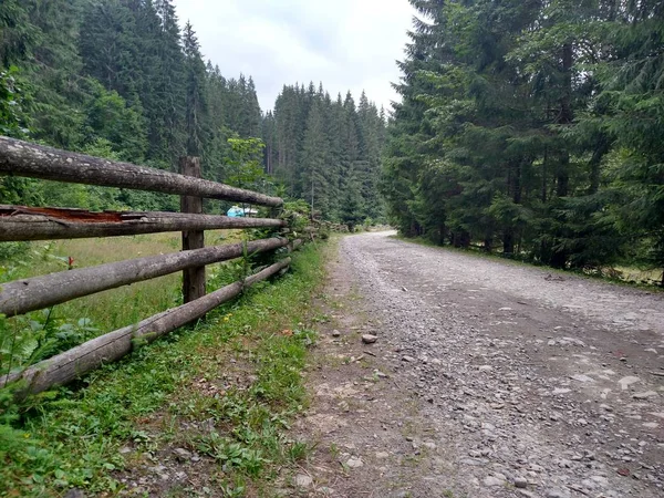 Onverharde weg in de buurt van een houten hek in de bergen Carpathians Wild Nature Village landelijk gebied — Stockfoto