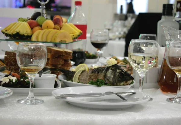 Stuffed fish, carp, on a serving table. There are also jugs with juices as well as various dishes. Good photos for the food industry and restaurant business.