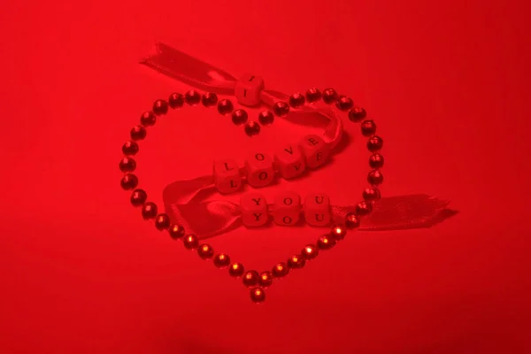 A red tape with the inscription of love, like an arrow breaks a heart made of red rhinestones. Original lighting is a beautiful composition, a wonderful photo of the day of Sainted Valentine.