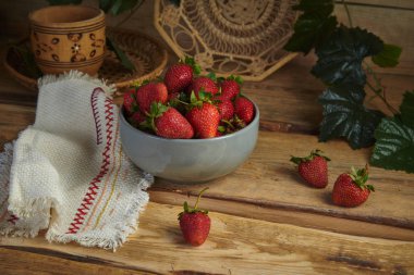 Natürmort hasır ware ahşap arka plan üzerinde bir gri kil kase çilek.