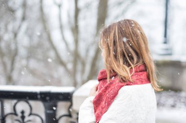 Kış aylarında düşen büyük kabarık kar taneleri ile şehir parkında duran kadın closeup