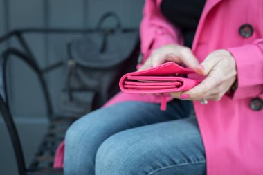 Pembe yağmurluklu kadın pembe cüzdan taşıyor.