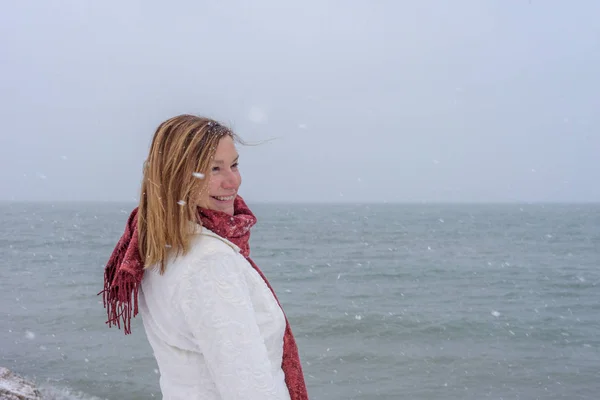 happy person standing along Lake Michigan shoreline in winter as fresh lake effect snow is falling