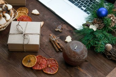 Bilgisayar ile kahverengi ahşap masa yer, Noel hediye kutuları, Kuru portakal, tarçın ve zencefil çerezleri üzerinde Noel.