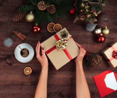 Noel işyeri üstten görünüm. Kızlar Noel yay ile mevcut tutan ahşap masa ellerde. Noel çelenk, dekorasyon, hediye ve süs eşyaları. 