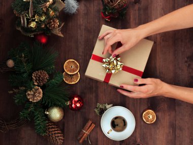 Noel işyeri üstten görünüm. Kızlar Noel yay ile mevcut tutan ahşap masa ellerde. Noel çelenk, dekorasyon, hediye ve süs eşyaları. 