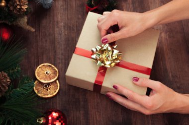 Noel işyeri üstten görünüm. Kızlar Noel yay ile mevcut tutan ahşap masa ellerde. Noel çelenk, dekorasyon, hediye ve süs eşyaları. 