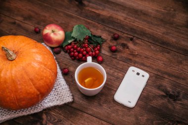 Autumn workplace, pumpkin, apples and book, phone on wooden table. clipart