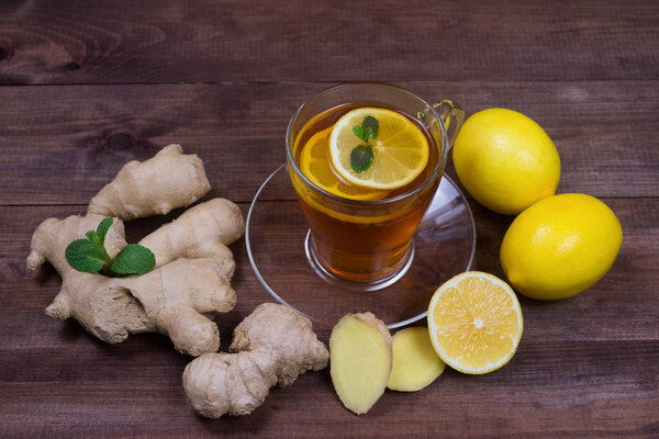 Ginger tea with lemon and mint on a wooden table.The concept of health.Drink rich of vitamins for winter time in cold days.
