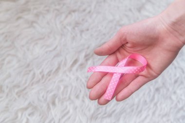 Beyaz arka planda pembe şerit tutan WOMANS elleri, meme kanseri Farkındalık ay, sağlık kavramı. 