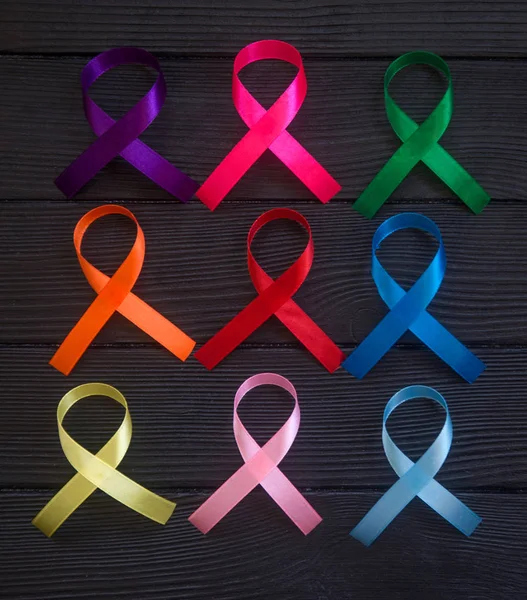 Cancer ribbons on black wooden background. Cancer awareness month.