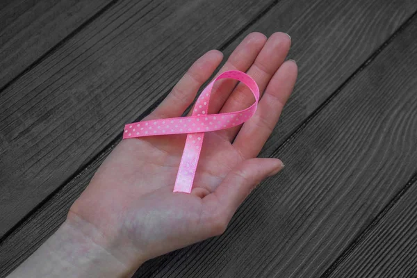妇女手拿着粉红色的丝带在黑色木背景 乳腺癌意识月 健康的概念 — 图库照片