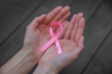  Siyah ahşap arka planda pembe şerit tutan WOMANS elleri, meme kanseri Farkındalık ay, sağlık kavramı. 