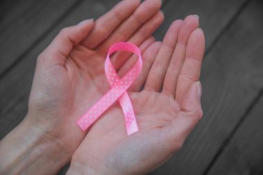  Siyah ahşap arka planda pembe şerit tutan WOMANS elleri, meme kanseri Farkındalık ay, sağlık kavramı. 