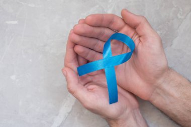 Mavi kanser şeridini tutan adam, prostat kanserinin sembolü. Sağlık ve tıp konsepti.
