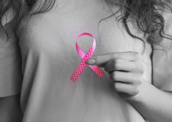 Womans hands holding pink ribbon, breast cancer awareness month, concept of health.