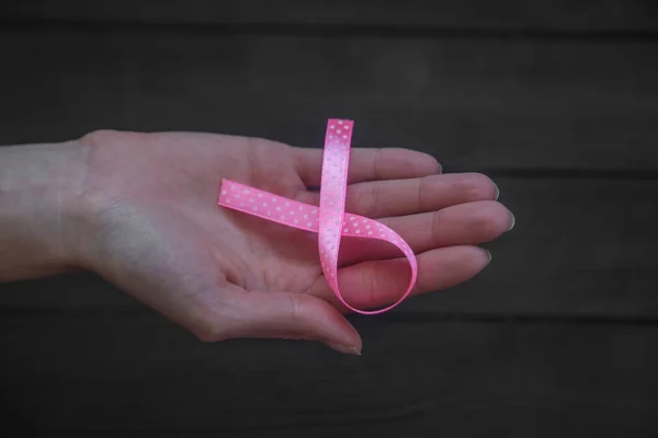 妇女手拿着粉红色的丝带在黑色木背景 乳腺癌意识月 健康的概念 — 图库照片