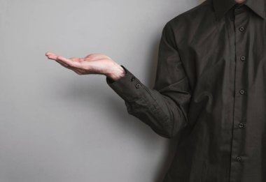 Kollarında bir şey tutan adam, gri arka plan üzerinde.