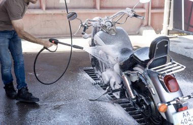 Adam su ve köpük ile oto yıkama bir motosiklet yıkar. 