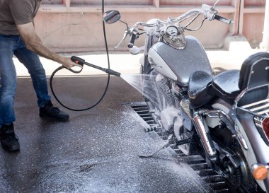 Adam su ve köpük ile oto yıkama bir motosiklet yıkar. 
