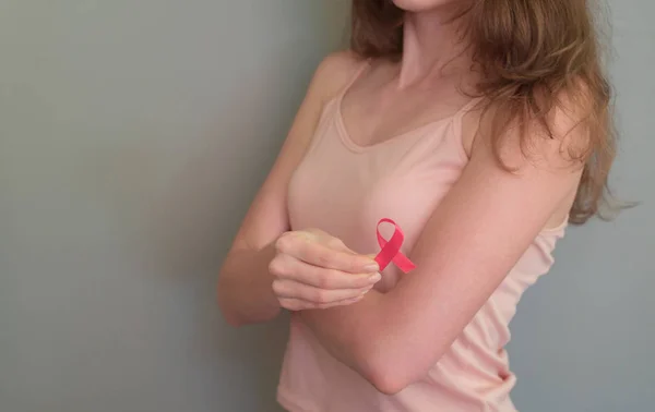 The girl holding a ribbon, symbol of cancer. Breast cancer awareness month.