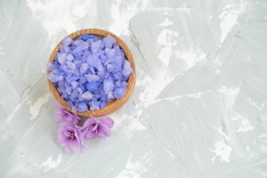 Gri arka planda banyo tuzu ve menekşe çiçekleri, spa tedavisi.