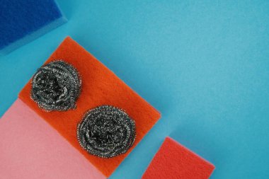 Mavi arka planda temizlik aksesuarları, süngerler, giysiler. Temizlik hizmeti kavramı. 