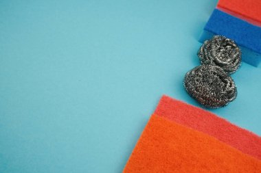 Mavi arka planda temizlik aksesuarları, süngerler, giysiler. Temizlik hizmeti kavramı. Boşluğu kopyala.