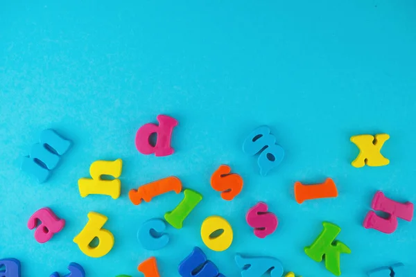 Plastic colourful alphabet letters on the blue background. Place for a text.