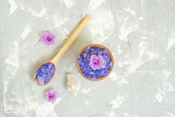 Wooden spoon and bowl with purple sea salt on grey background.Background for advertising salty.