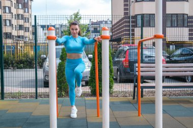 Spor salonunun bahçesindeki yatay barda egzersiz yapan kız.