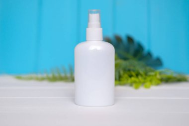 Mavi ahşap masadaki antiseptik için beyaz şişe, modaya uygun bir model, metin için yer..