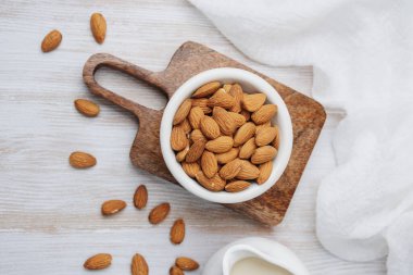 Tahta tahtada, beyaz bez ve sürahi ile taze bademler.