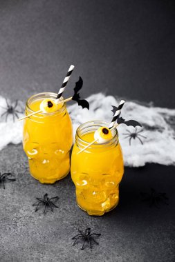 İki kafatası kavanozunda portakallı Cadılar Bayramı içkileri göz süslemeleri, yarasalar ve ürkütücü örümcekler var..